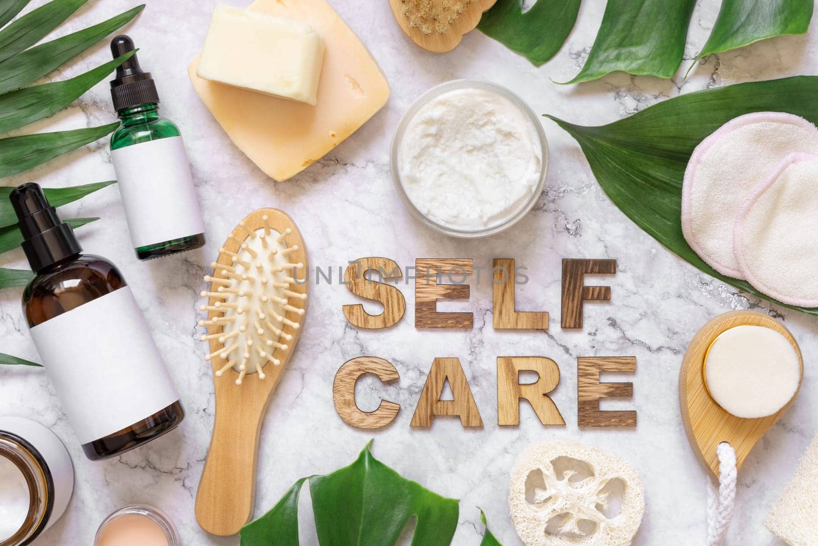 Self Care text near cosmetics, skin and hair care accessories and monstera leaves, copy space. Brand package mockup. Natural beauty products, Top view