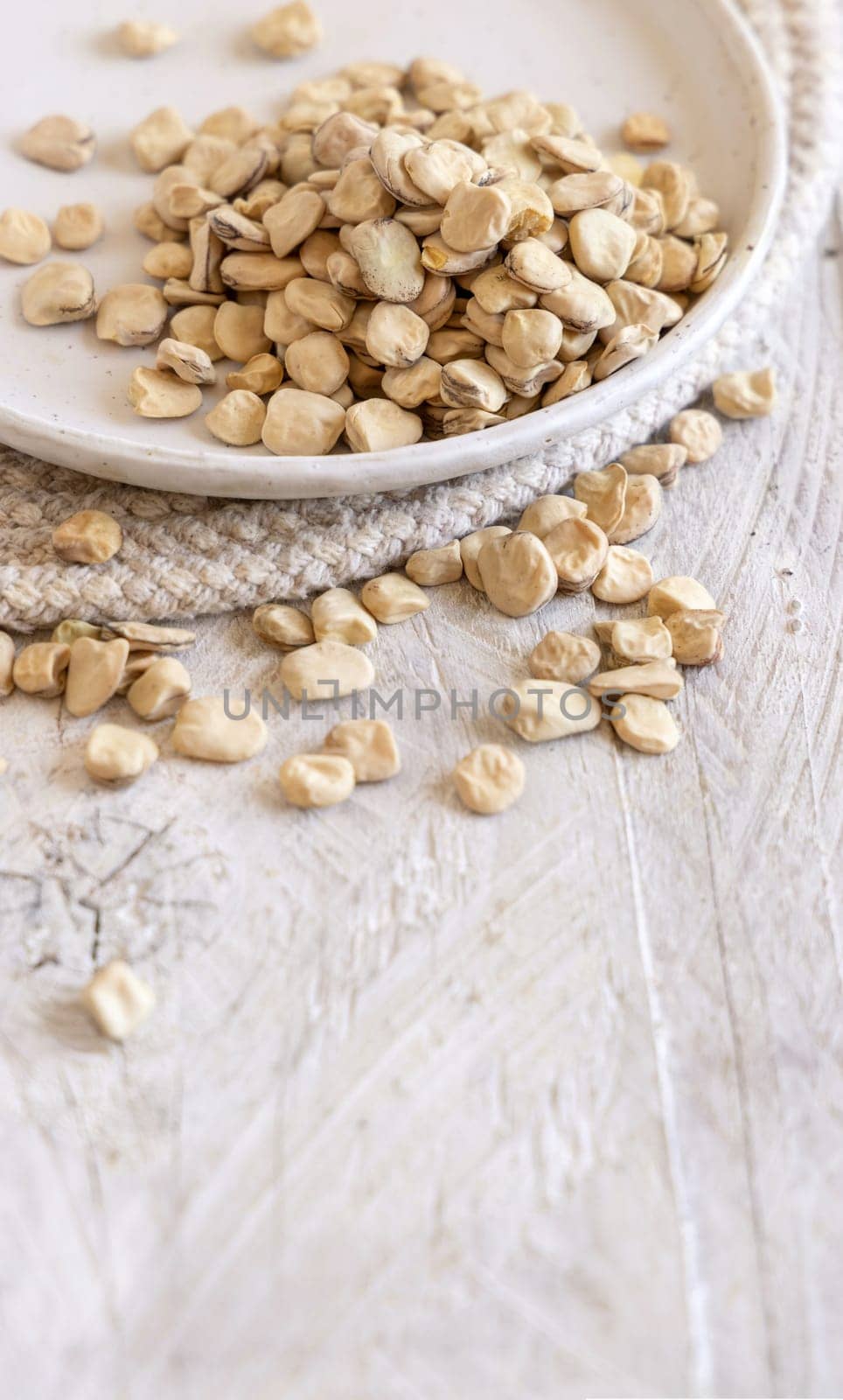 Plate of raw dry Grass pea close up on wood. Healthy, protein source for vegan and vegetarian diet. Traditional Italian apulian cuisine ingredient. Legumes known as Cicerchia, Vetch, Blue Sweet Pea
