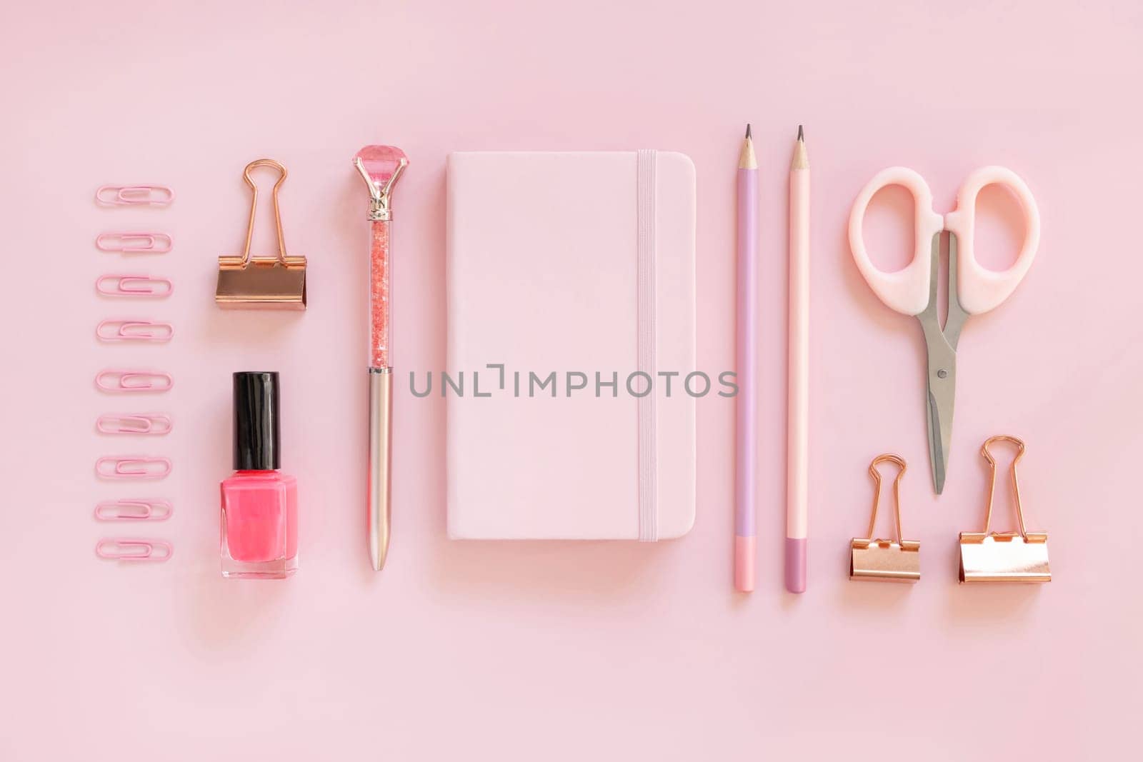 Hardcover notebook and Pink school accessories on pastel pink, Top view, textbook mockup. Girly workplace with scissors, pencils, pen, paperclips and nail polish. Back to school concept