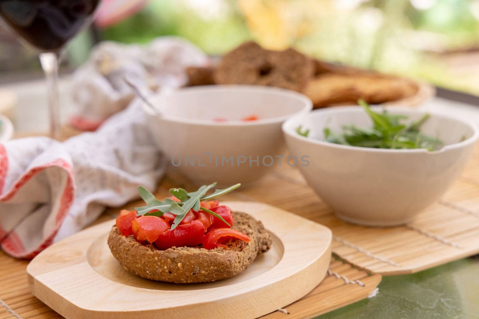 Italian summer appetizer Friselle with cherry tomatoes, oil and rucola served outdoor with glasses of red wine. Tipical Apulian Dried bread, made in Salento. Local cousine. Vegetarian food