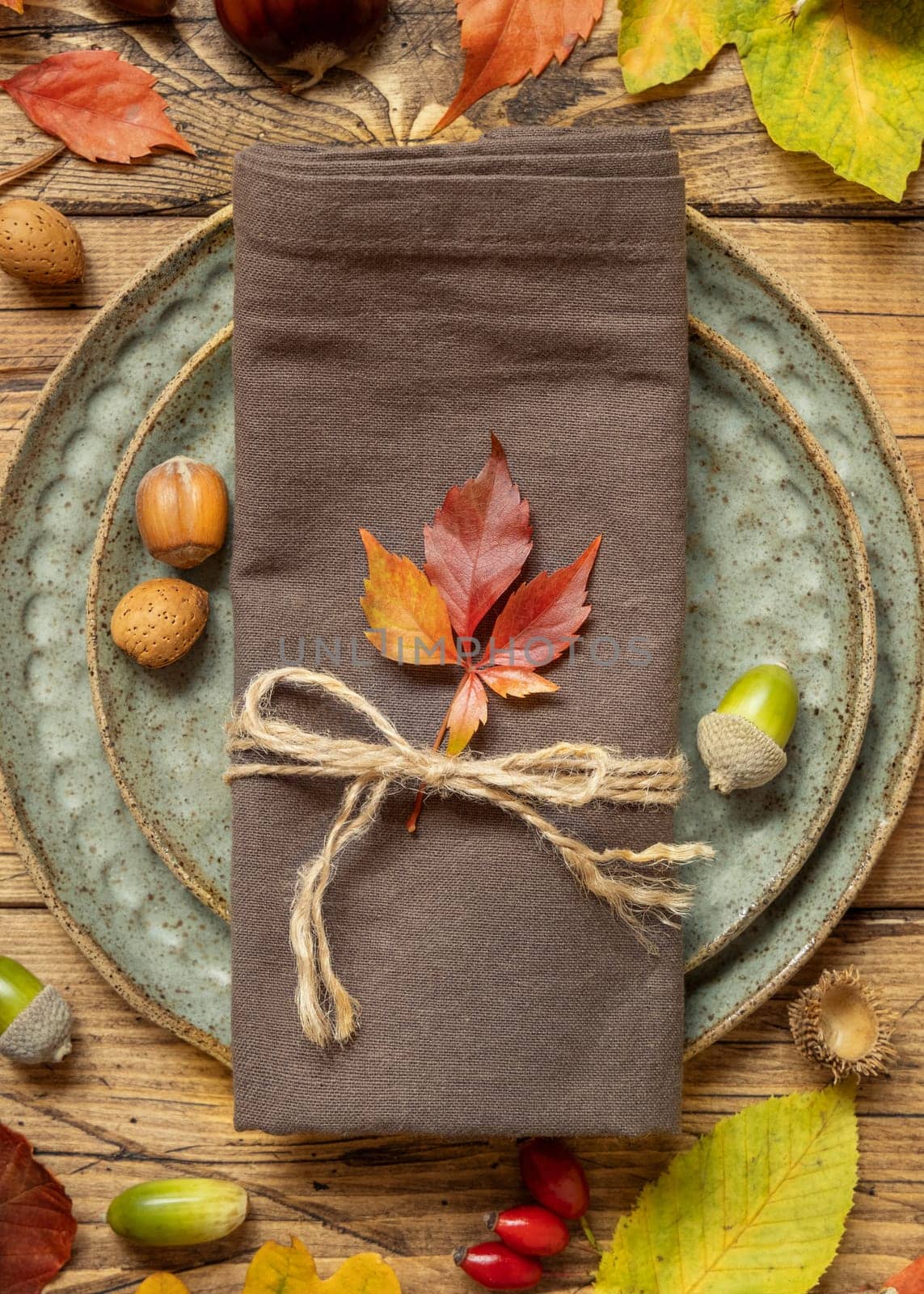 Autumn rustic table setting between leaves and berries on vintage wooden table top view. Thanksgiving, halloween or harvest concept