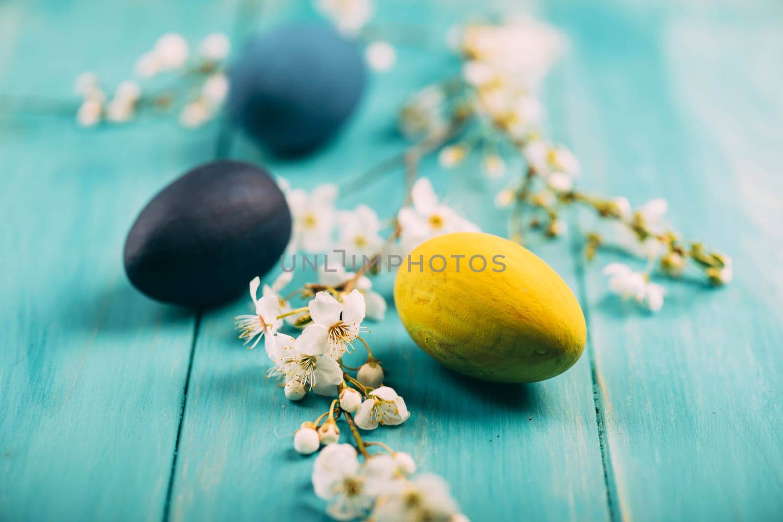 Hand painted colorful easter eggs decorated with spring cherry blossoms on wooden background.
