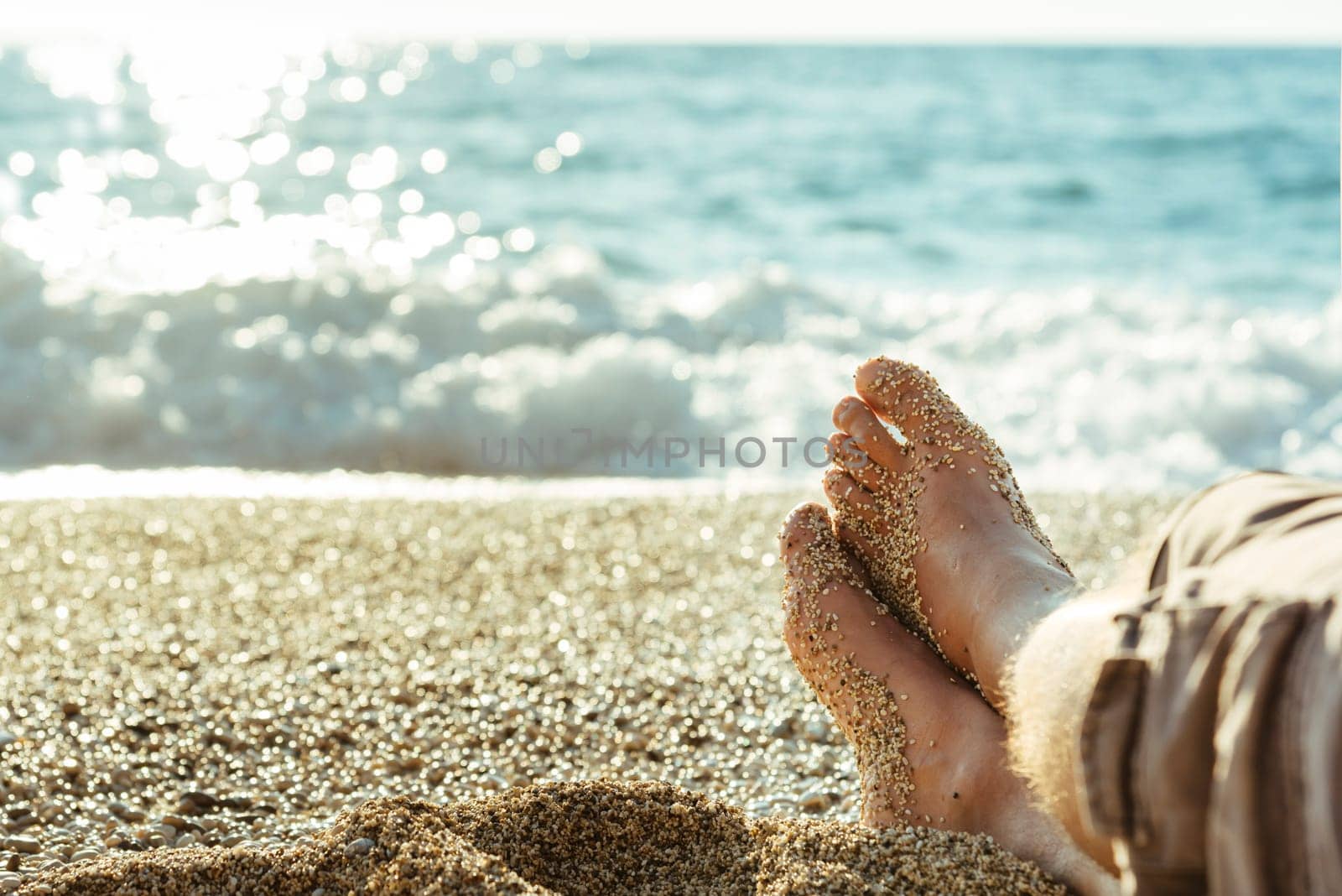 Closeup of male legs on the sandy beach.