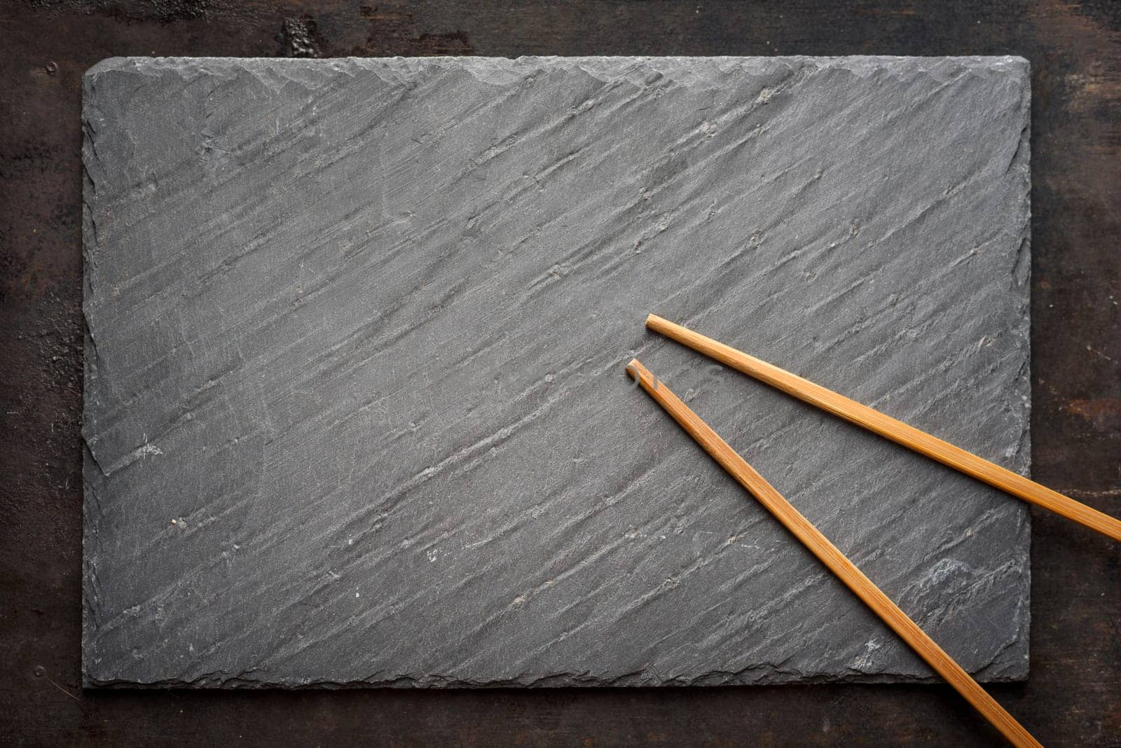Black sushi slate board with wooden chopsticks with copyspace. Top view.
