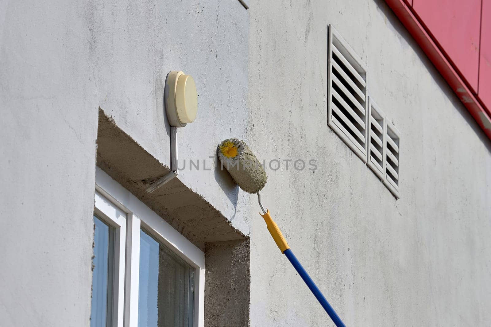 painting the street wall with a roller with gray paint. High quality photo