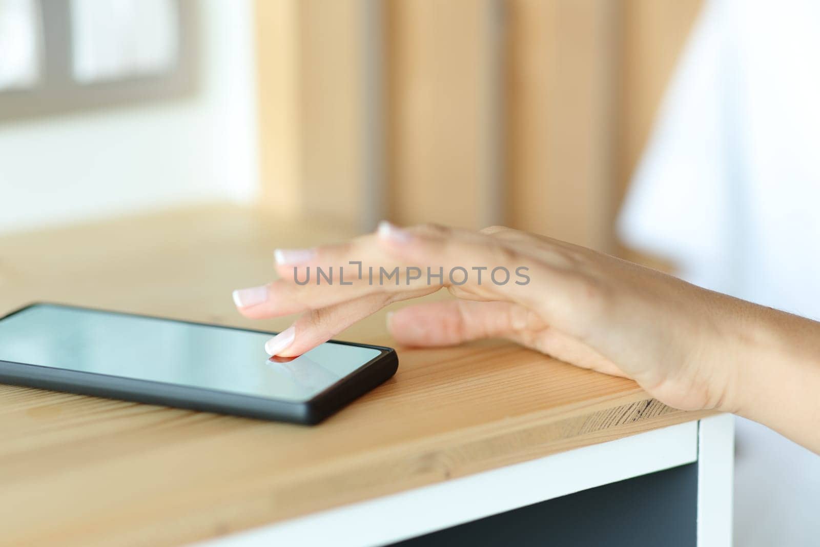 Close up portrait of a woman hand stopping alarm on smart phone in a bedroom