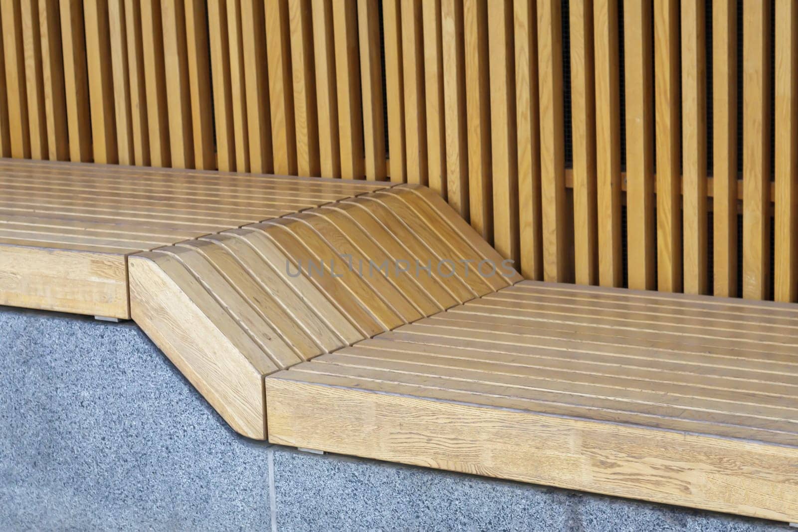 Empty modern wooden benches without people on a sunny day, public places in the city park. City improvement, urban planning, public spaces, recreation area. City public anti-vandal furniture for rest