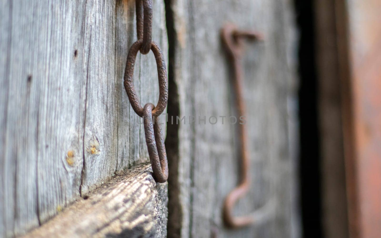 Isolated old rusty door latch on a wooden door. Close-up. Problematic weathered panels. Old wall texture background. Detail of an old wooden door with a rusty door latch