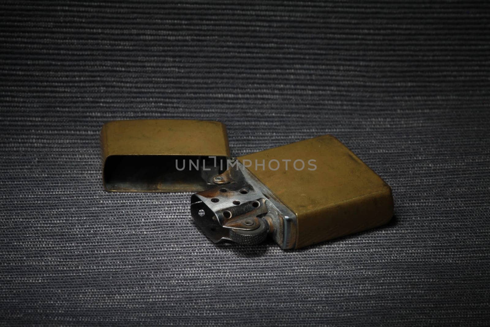 old brass petrol lighter with flint and an open lid on a dark background still life