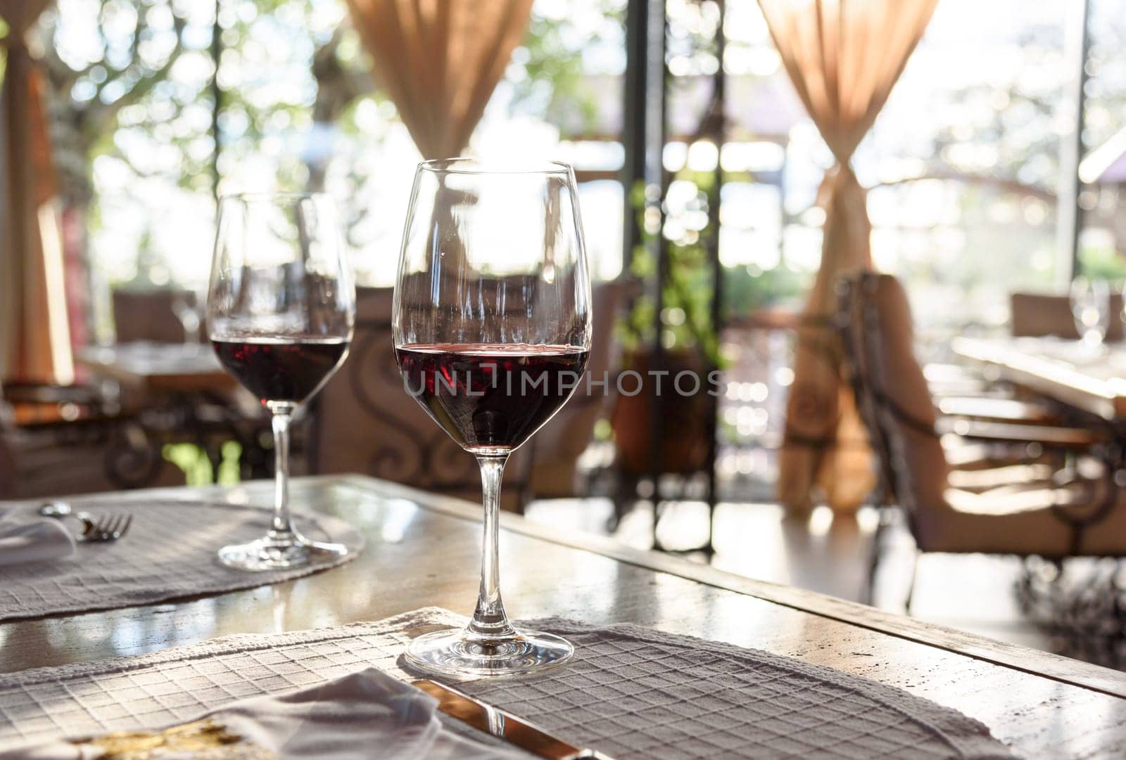 Fancy restaurant interior and served table with two glass of red wine.