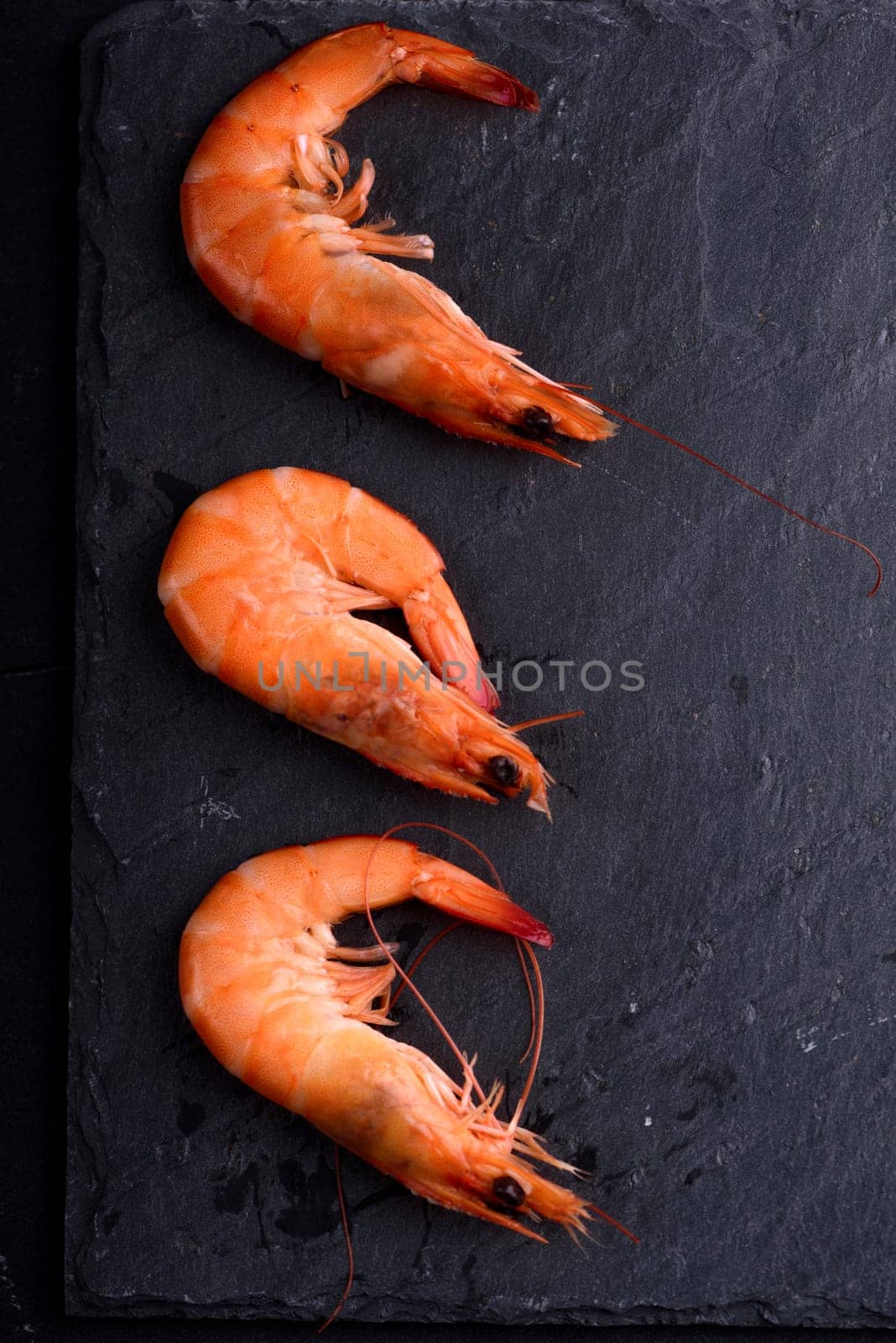 Top view of fresh shrimps on black stone slate with copyspace. Seafood ingredients  preparation.