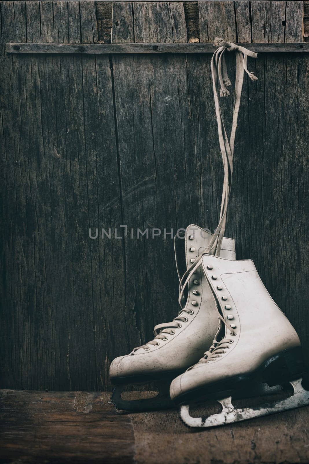 Seasonal winter holiday scene with pair of white  ice skates on rustic wooden background with copyspace.