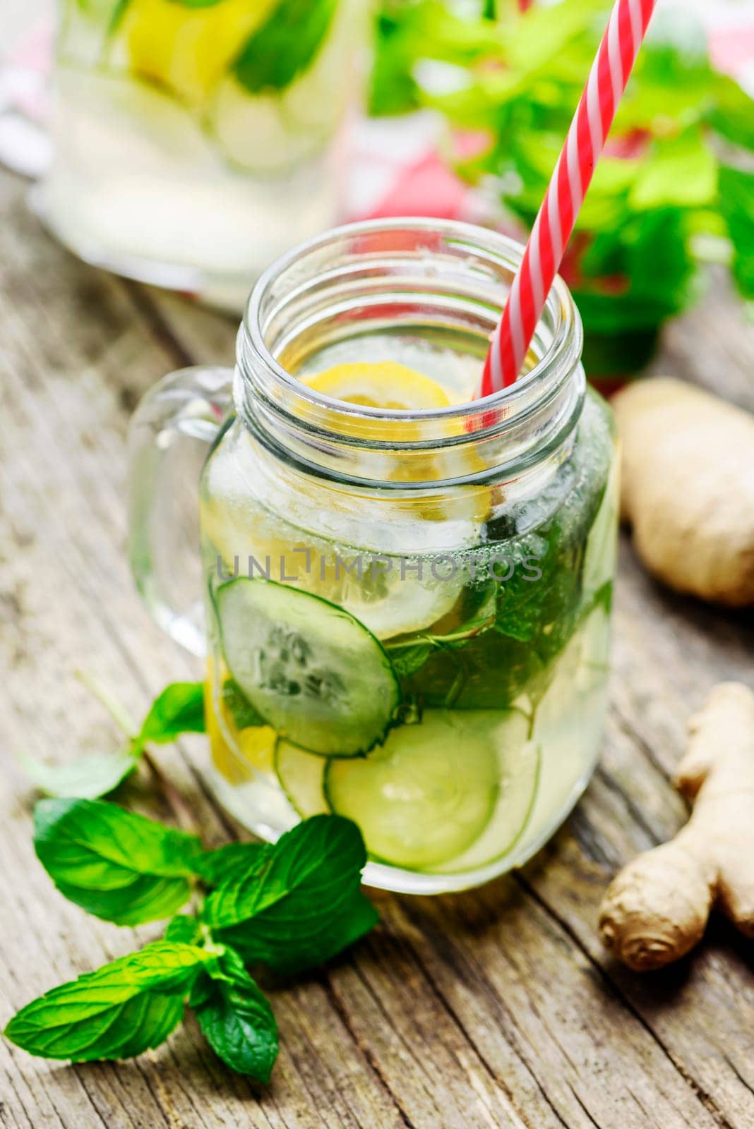 Detox drink with water, cucumber, lemonade and mint in mason jar glass with retro straws.