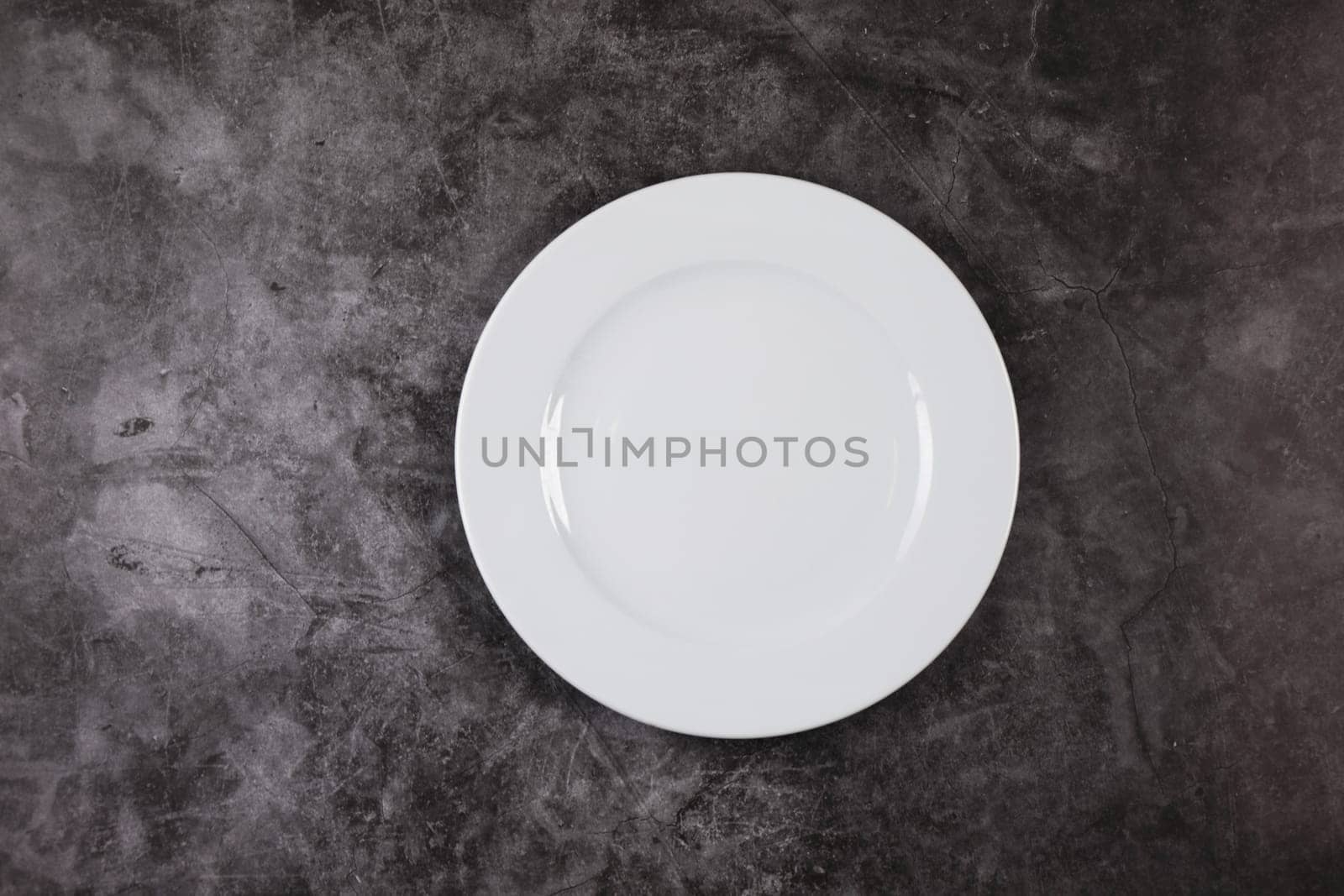 A white dinner plate on a grey and white marble surface