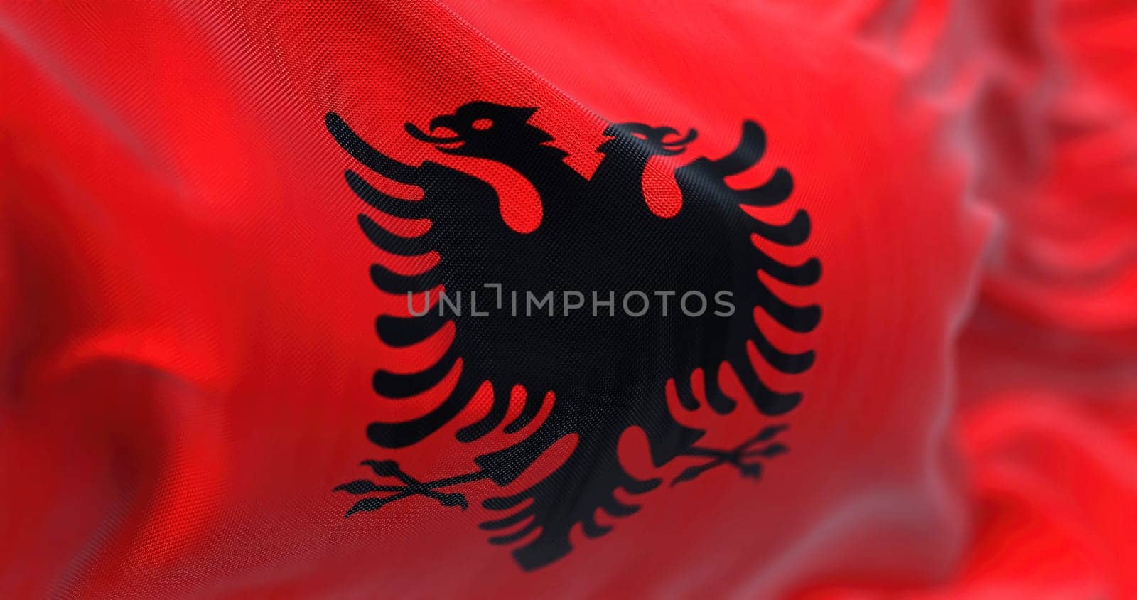 Close-up view of the Albanian national flag waving in the wind. Albania is a country in Southeastern Europe. Fabric textured background. Selective focus
