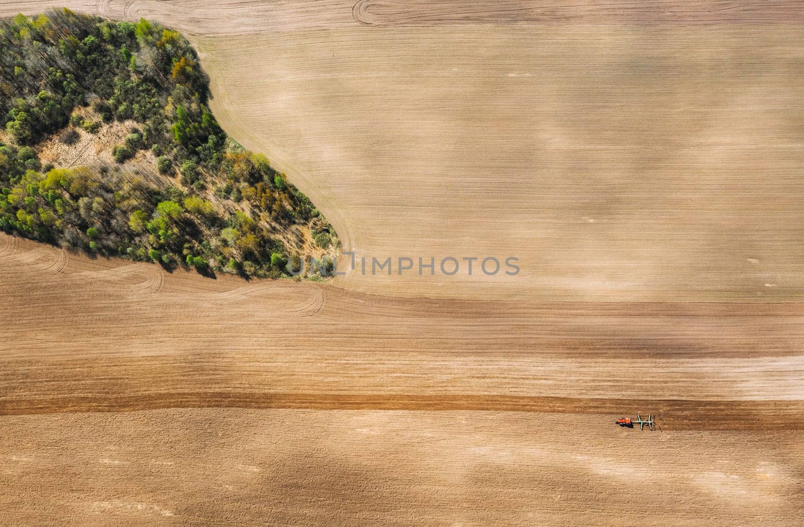 Tractor Plowing Field In Spring. Beginning Of Agricultural Season. Cultivator Pulled By A Tractor In Countryside Rural Field. Countryside Field Landscape. Aerial View. Top Flat View.