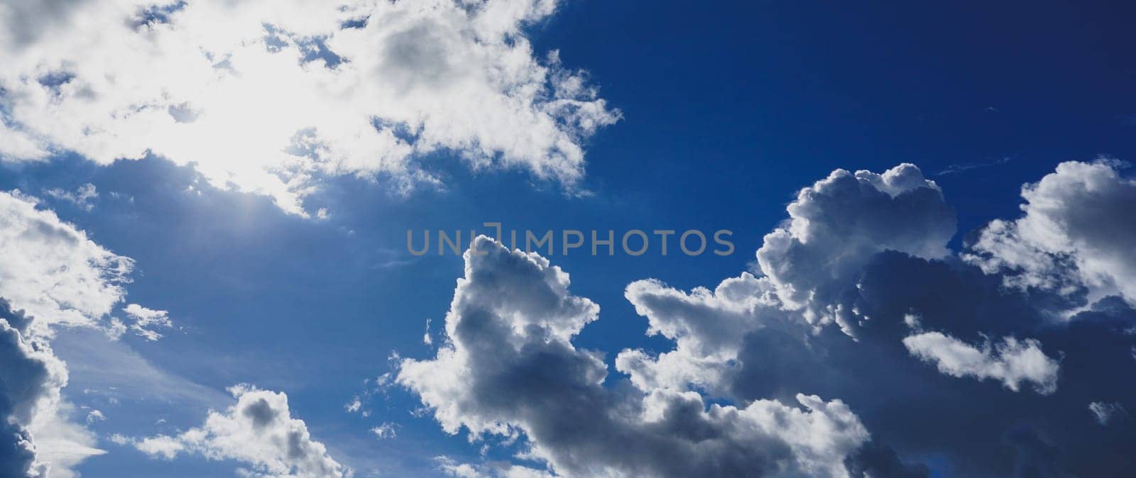 Blue sky with clouds and sun shines bright in the daytime in summer