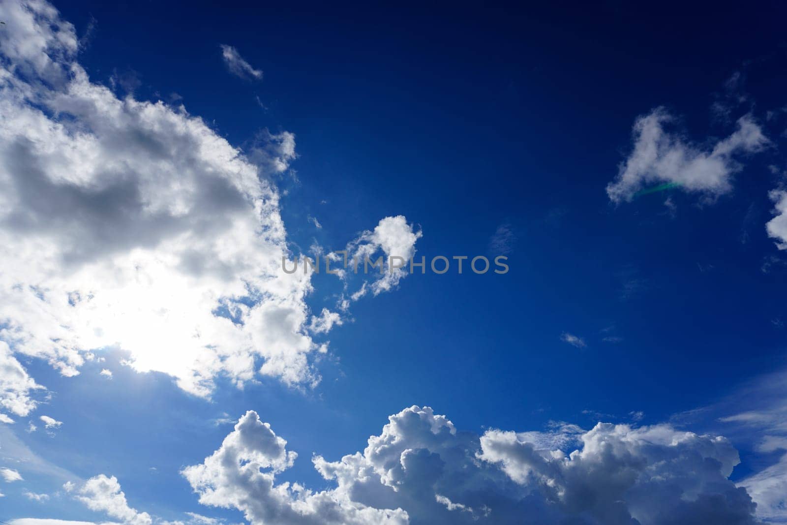 Blue sky with clouds and sun shines bright in the daytime in summer