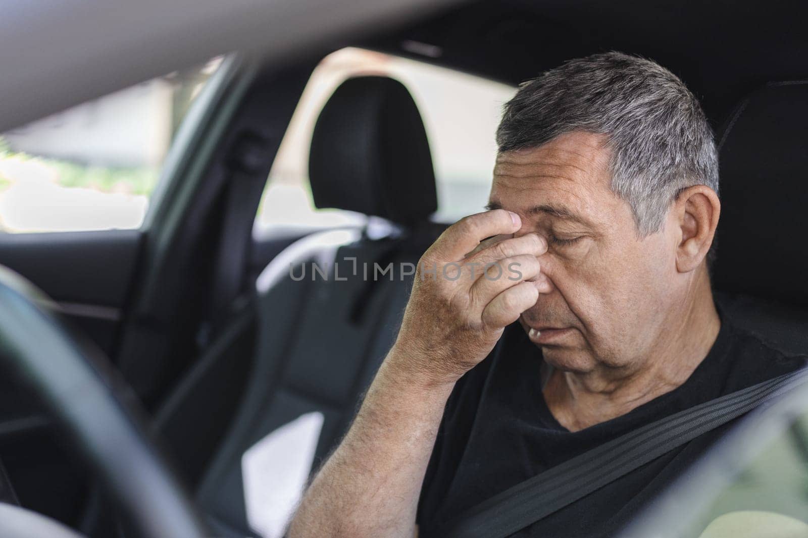 Tired pensioner in his 70s, dring in a car