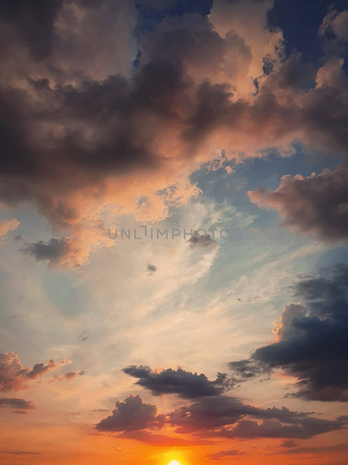 Wonderful colored sunset sky with tiny sun over the horizon, vertical celestial background