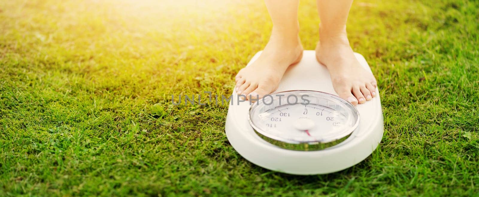 Woman standing on the white scales with bare feet in nature. Concept of the weight loss and healthy lifestyle.