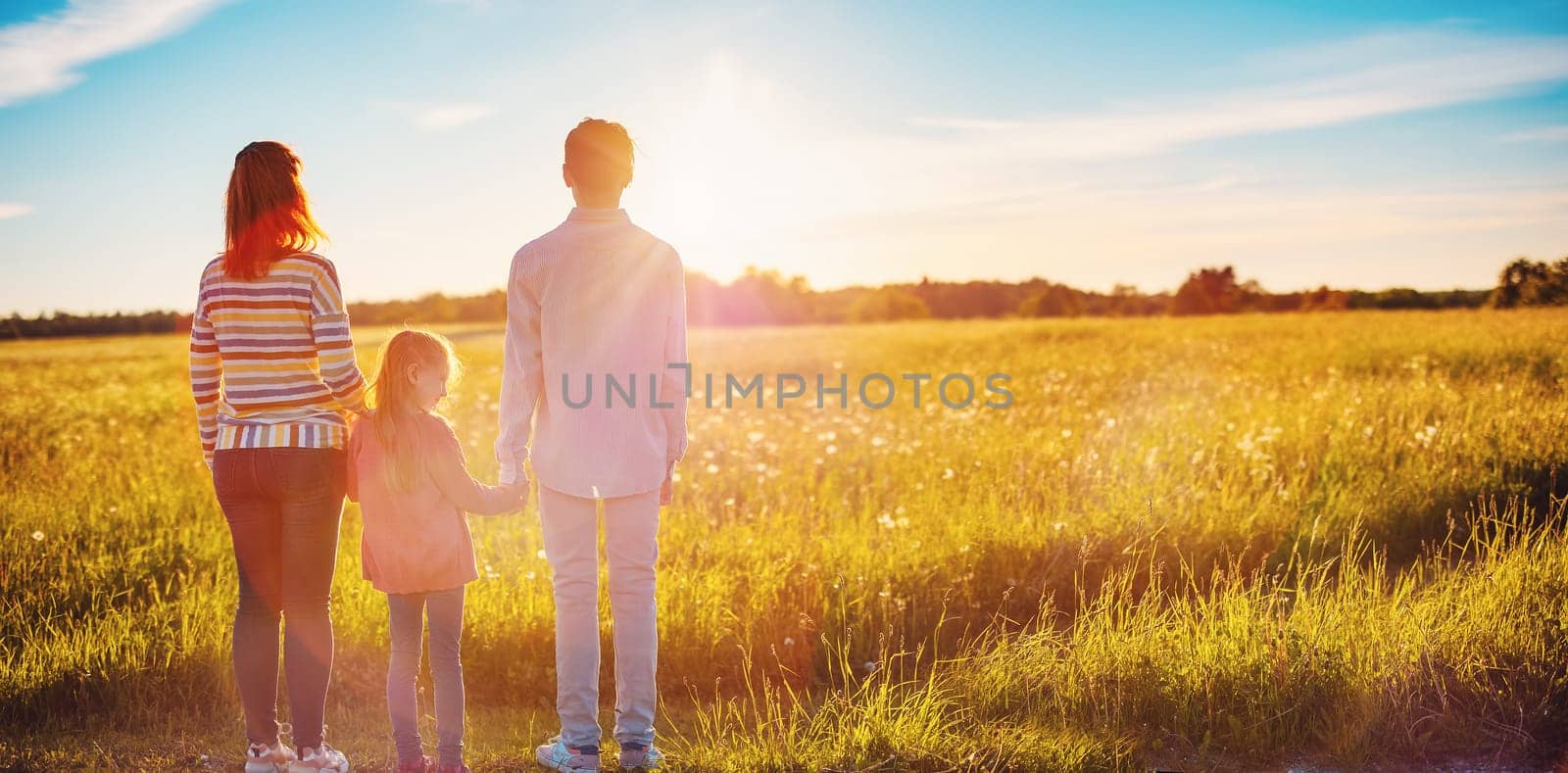 Happy family in the nature together on the evening sunset. Panoramic view. Concept of the vacation and relationship.