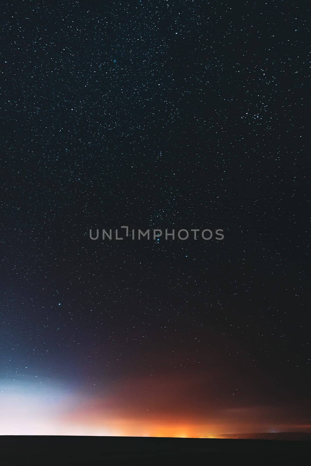 Night Starry Sky With Glowing Stars Above Countryside Landscape. Rural Field Meadow In Early Spring. Bright Glowing Stars.