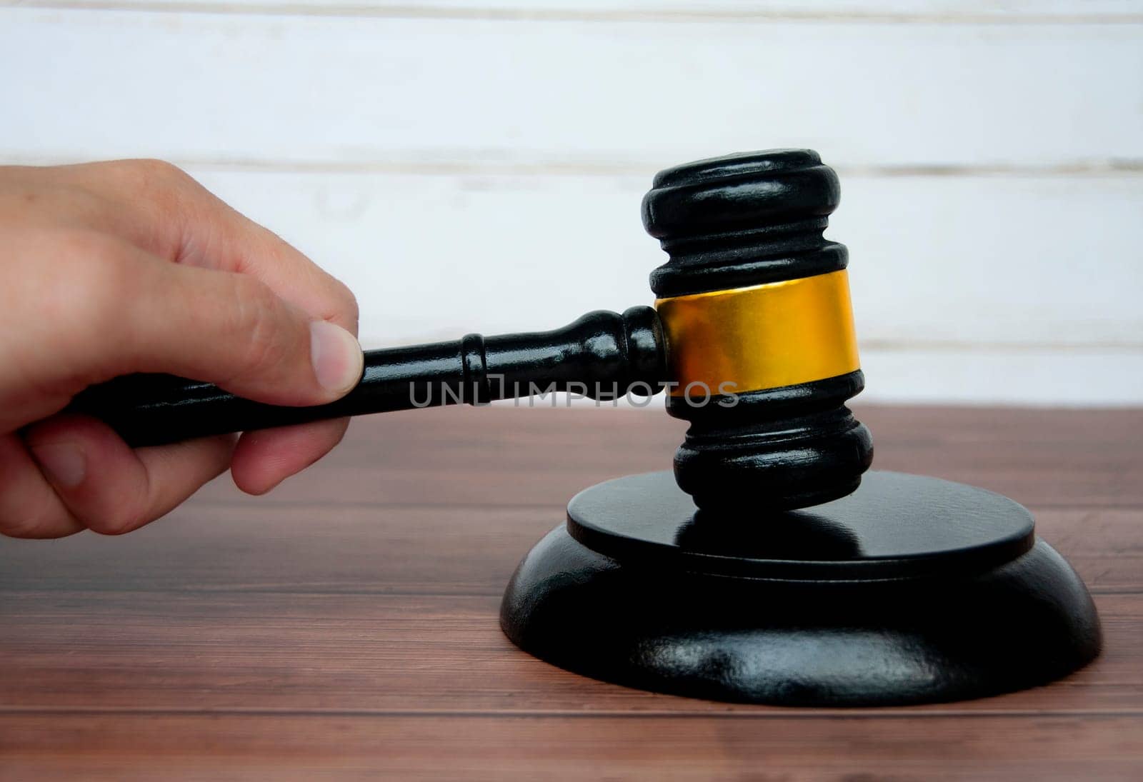 Hand holding lawyer gavel on wooden table background. Law and order concept