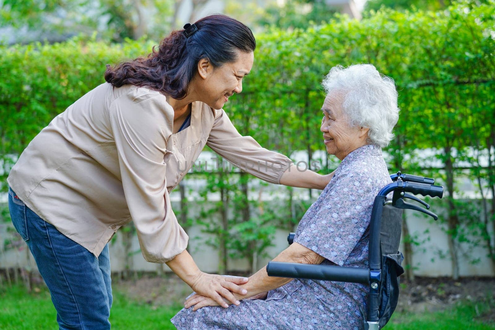 Caregiver help Asian elderly woman disability patient in nursing hospital, medical concept.