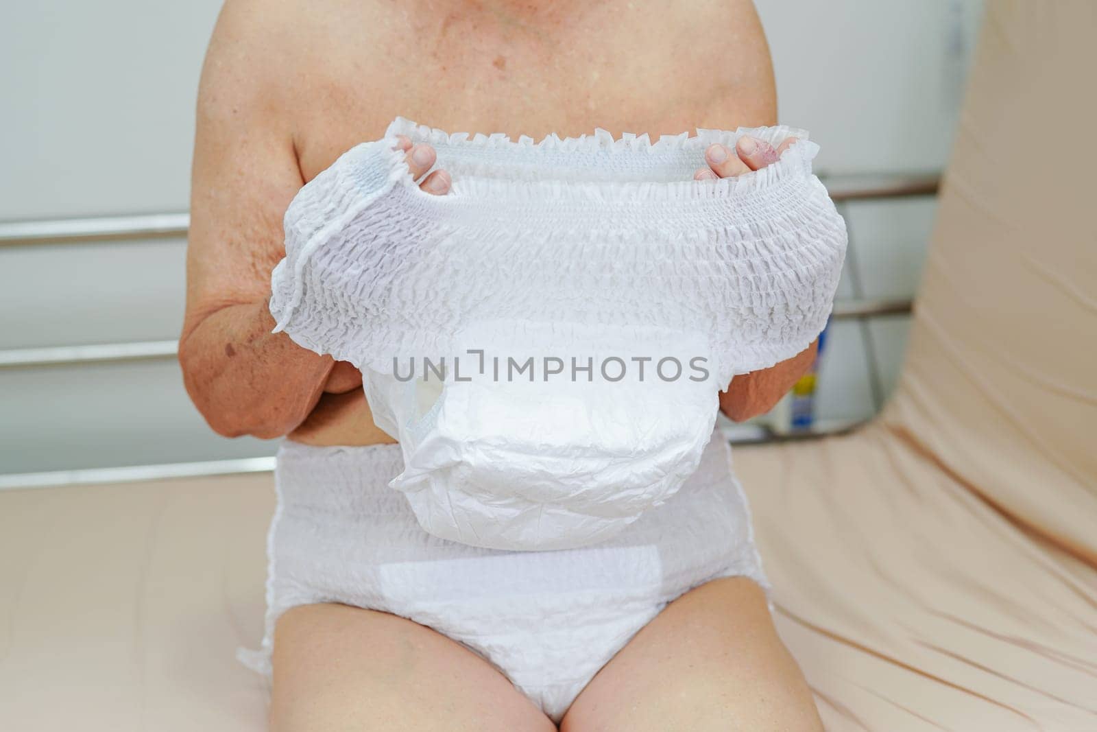 Asian elder senior woman patient wearing adult incontinence diaper pad in hospital.