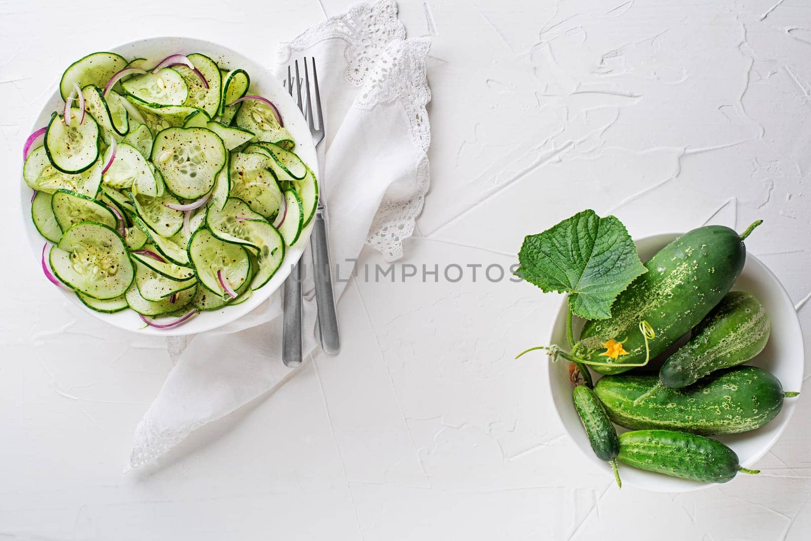 Fresh Cucumber salad with dressing on white table background