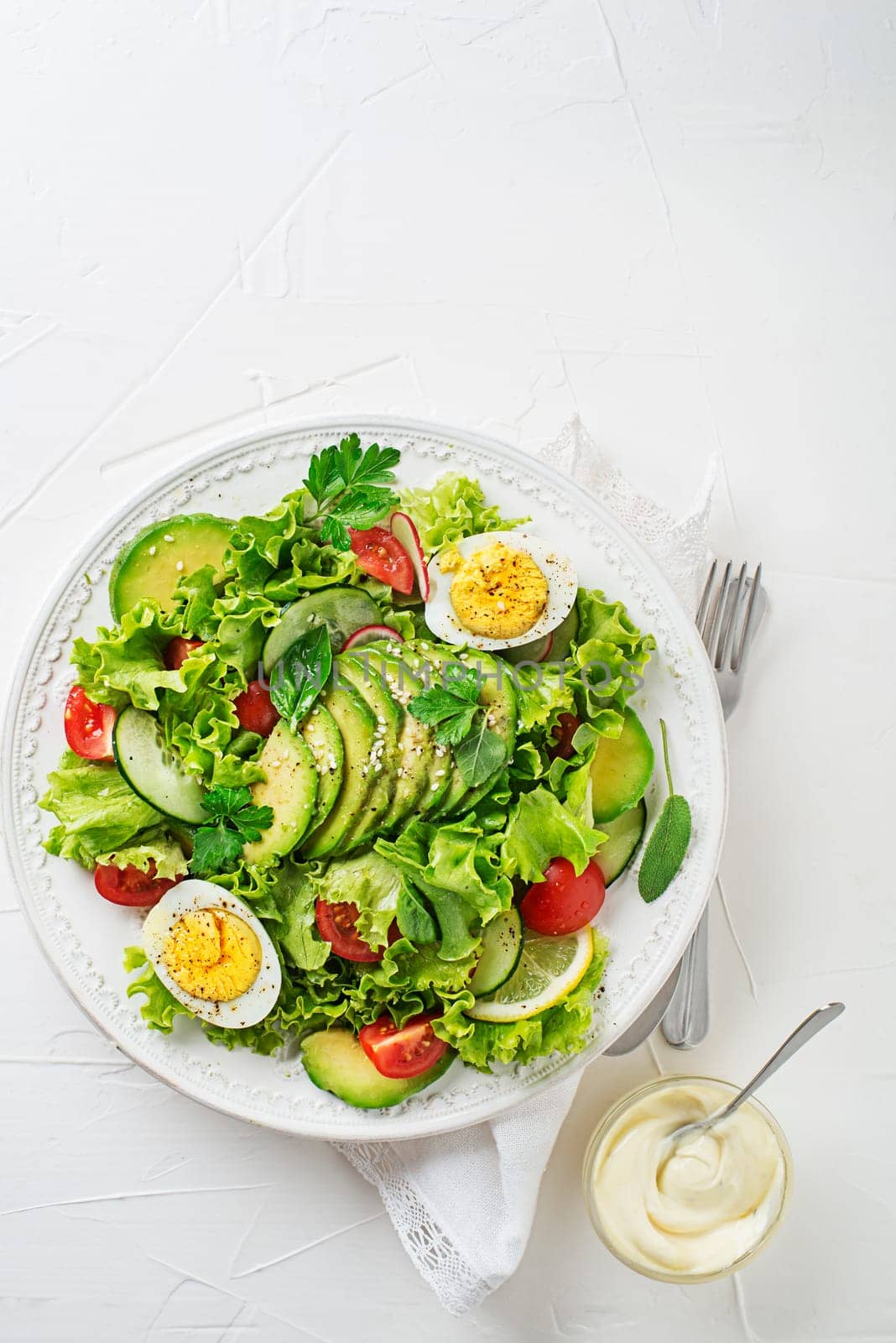 Green mixed salad with avocado, egg and fresh vegetables with creamy dressing
