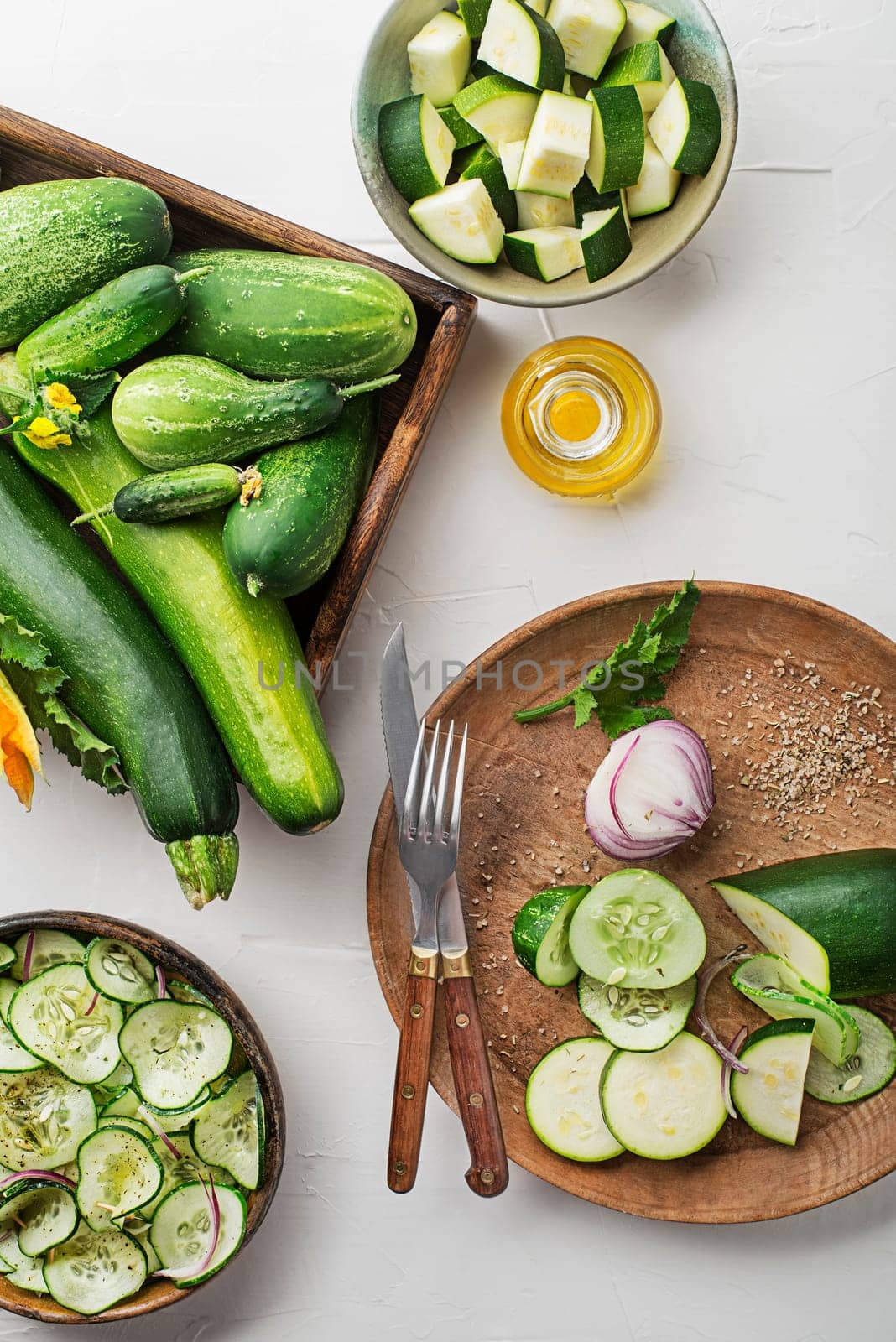 Slicing fresh vegetable crops. Preparing healthy meal with zucchini and cucumber. Ripe zucchini and cucumber on white table background