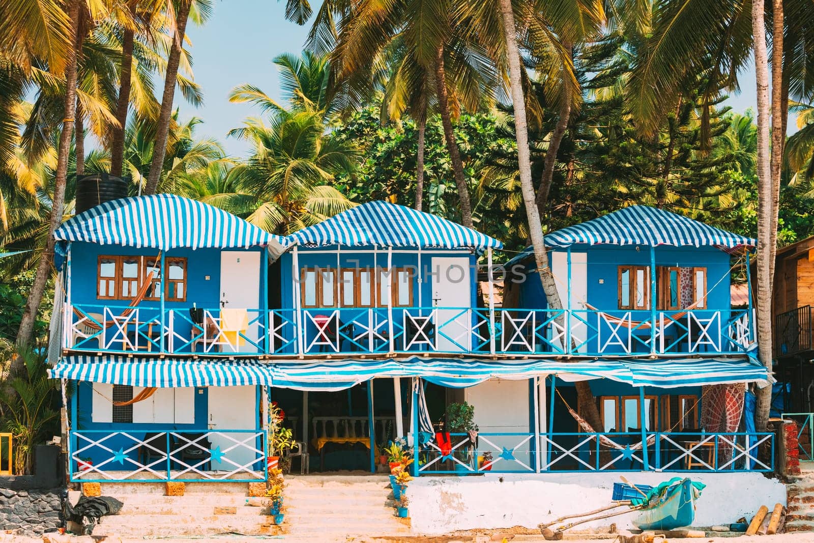Canacona, Goa, India. Famous Painted Guest Houses On Palolem Beach Against Background Of Tall Palm Trees In Sunny Day.