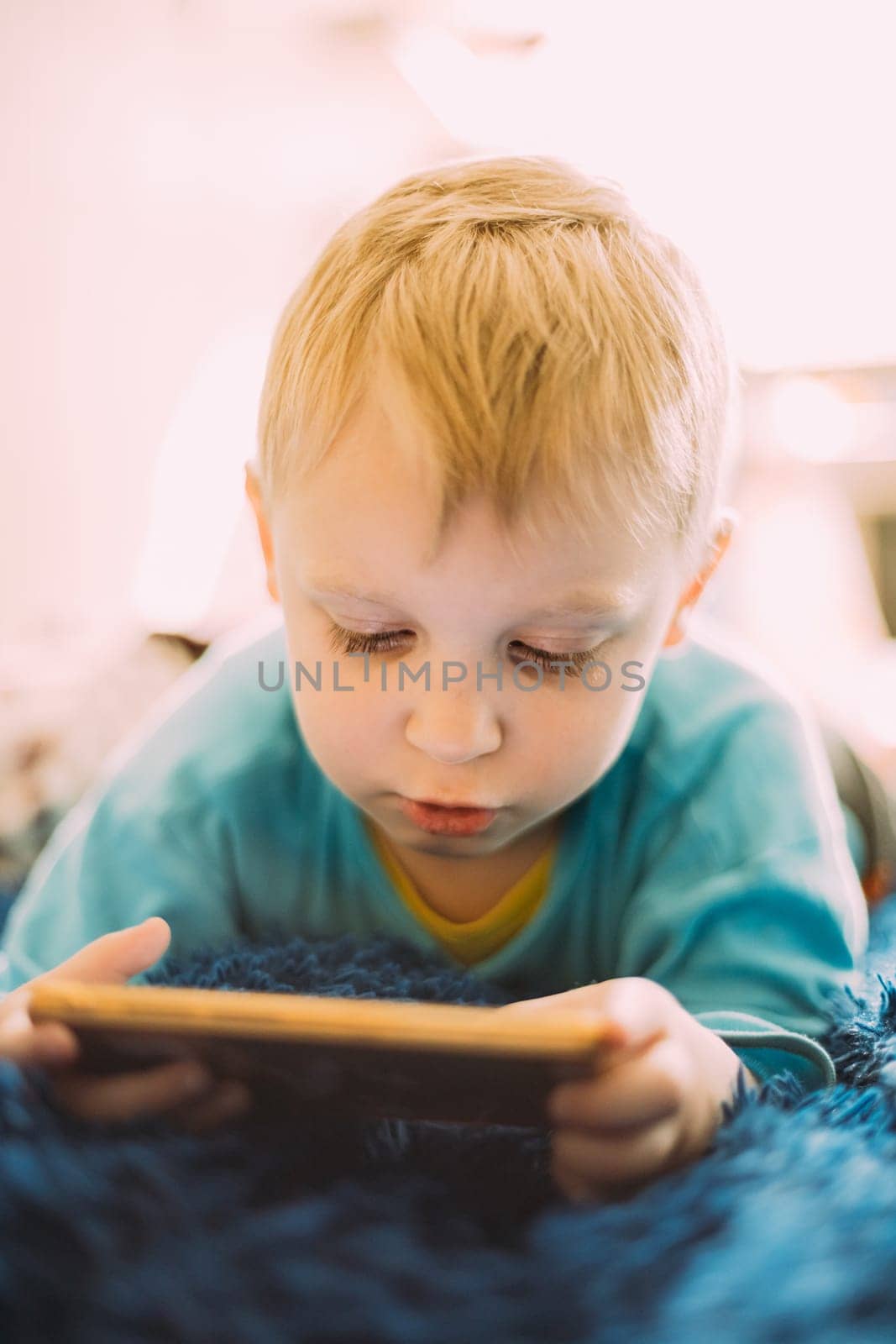 Little Blond Boy Playing Games On Phone.