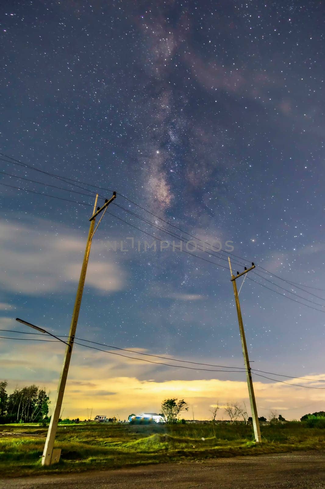 Electric poles in the nighttime countryside, the sky with stars and beautiful taro scenes, clouds below the horizon above the grass