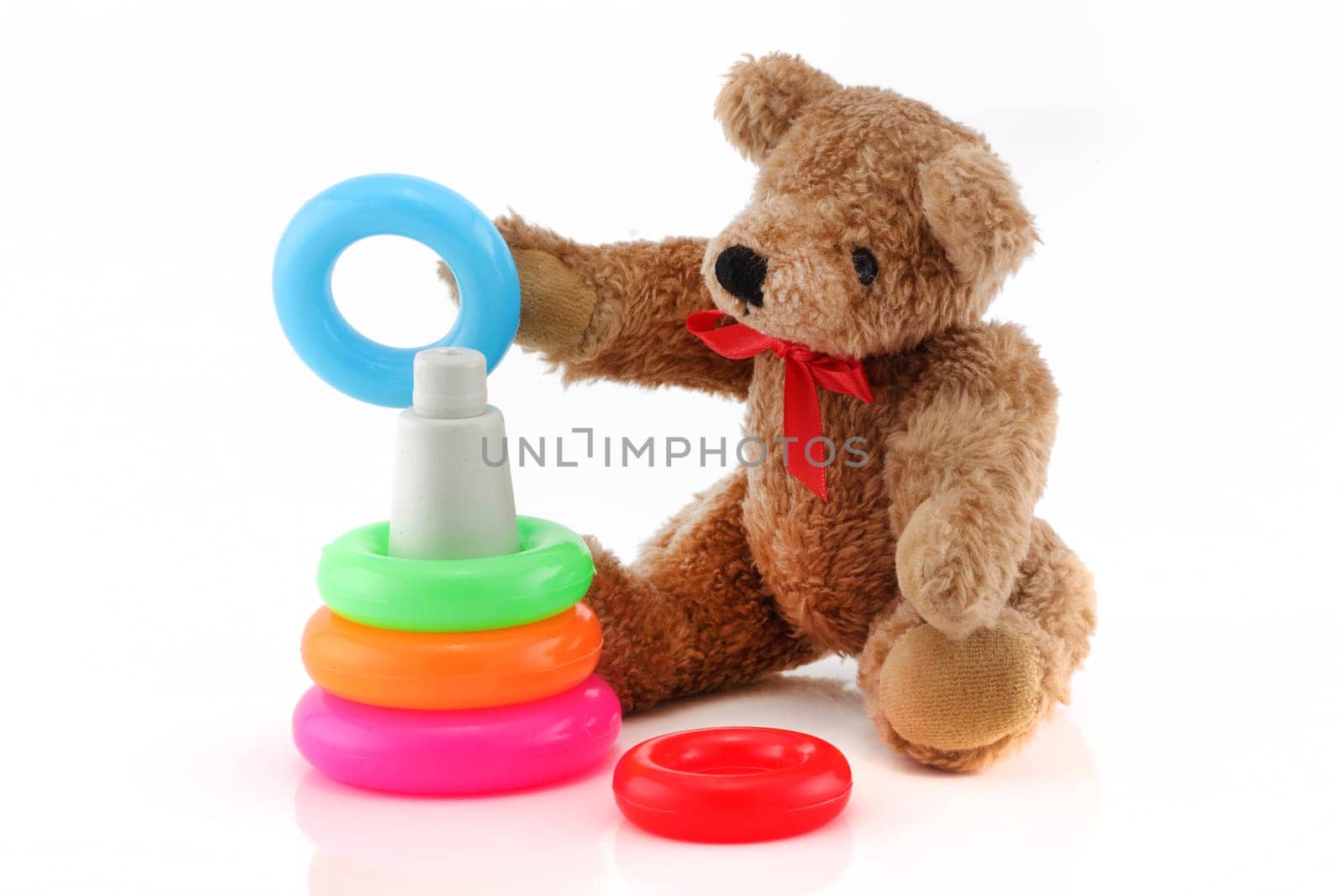 A cute teddy bear playing with toy rings