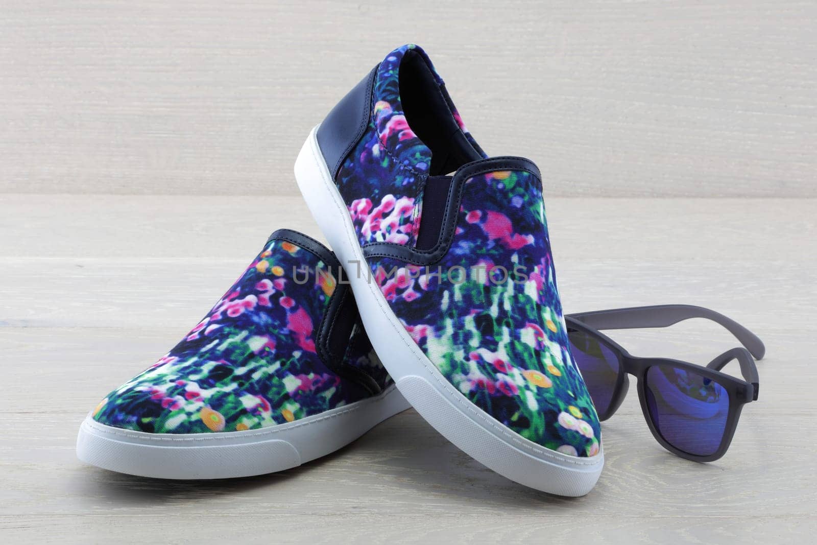 A pair of colourful pumps on wood background with sunglasses