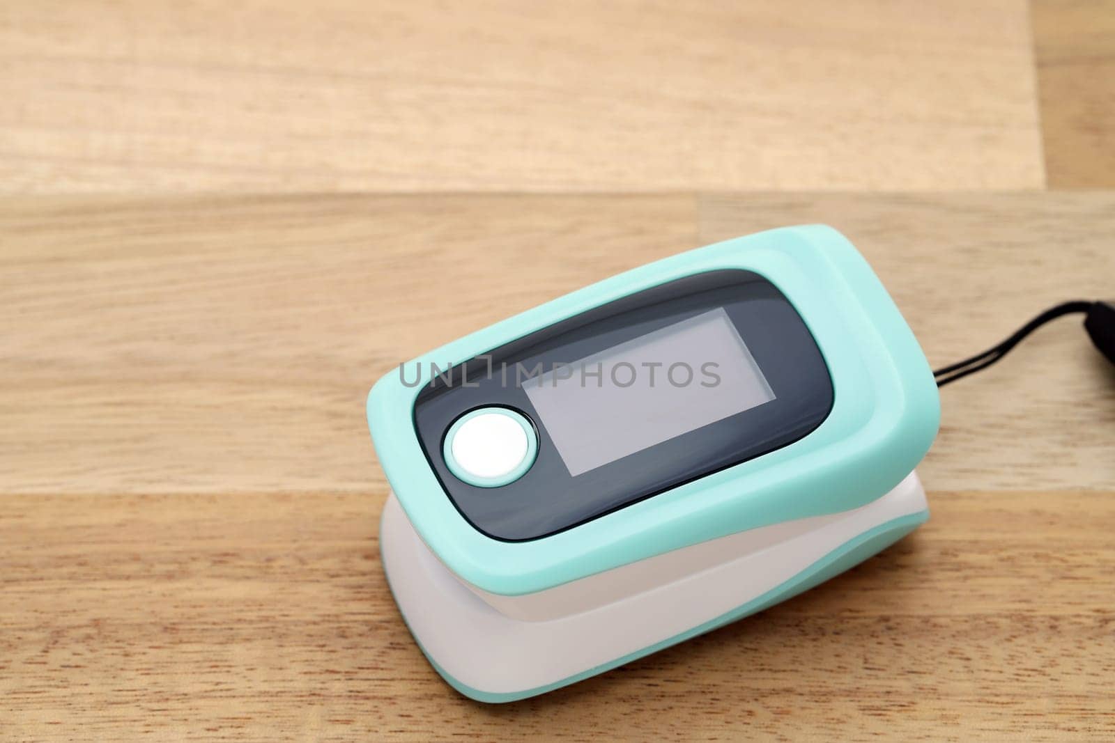 Pulse oximeter device on wooden table, healthcare monitoring concept