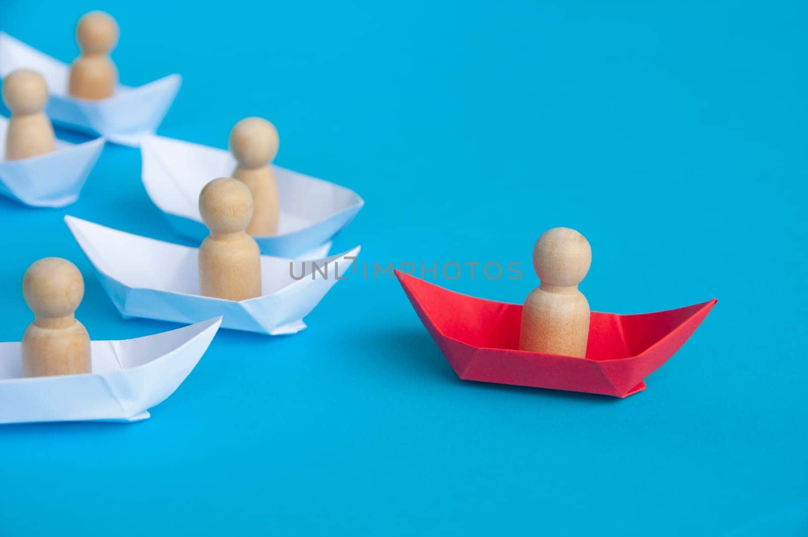 Leadership concept - Wooden doll on paper ship leading the rest of the ships.