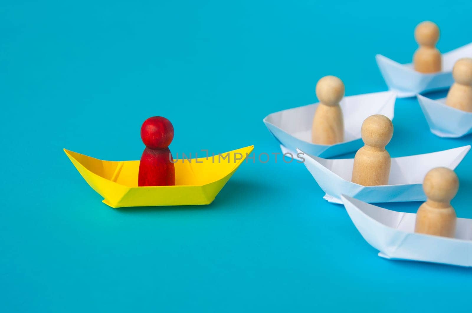Leadership Concept - Red people figure on yellow paper ship origami leading the rest of the people figure on white paper ship. Copy space.