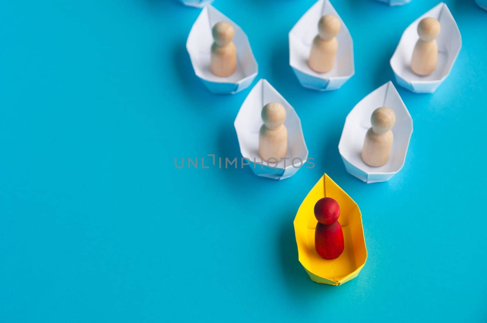 Leadership Concept - Red people figure on yellow paper ship origami leading the rest of the people figure on white paper ship. Copy space.