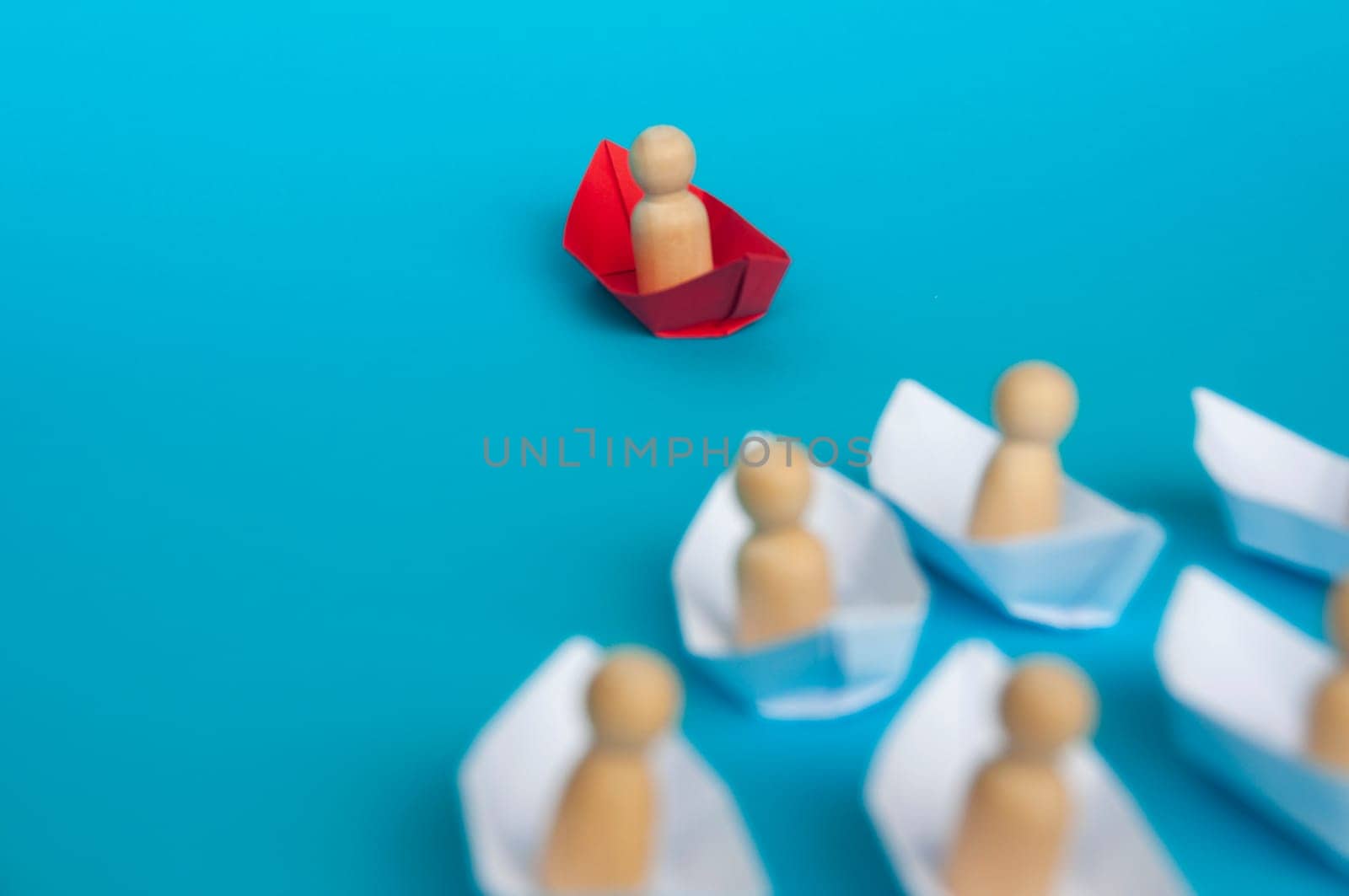 Leadership concept - People figure on red paper ship origami leading the rest of the people figure on white paper ship. Copy space.