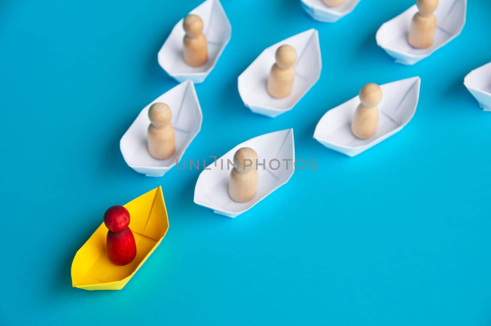 Leadership Concept - Red people figure on yellow paper ship origami leading the rest of the people figure on white paper ship. Copy space.