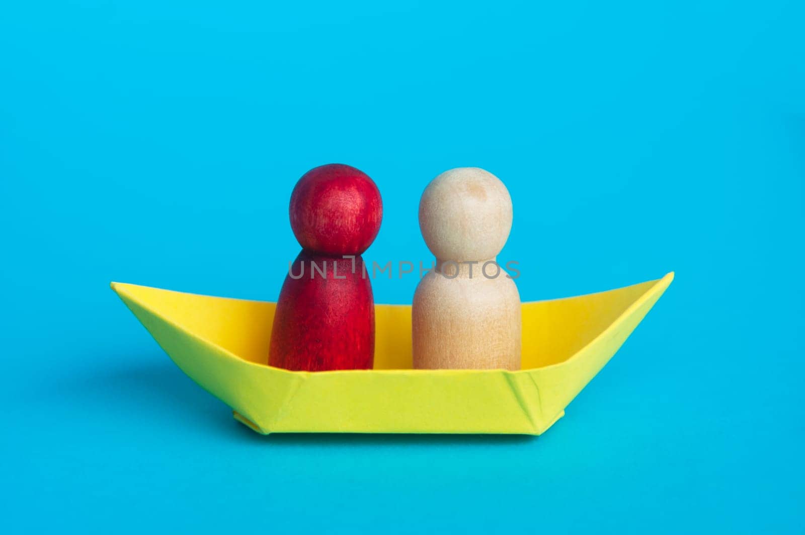 Couples on yellow paper ship with blue background. Relationship concept.