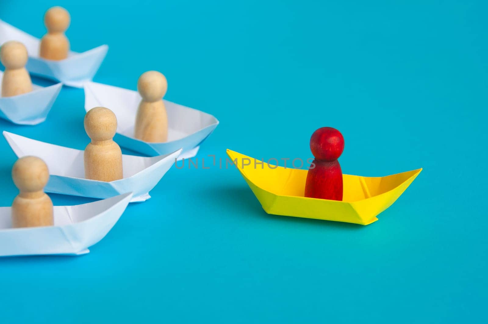 Red wooden doll on yellow paper ship leading the rest of the ships - Leadership concept