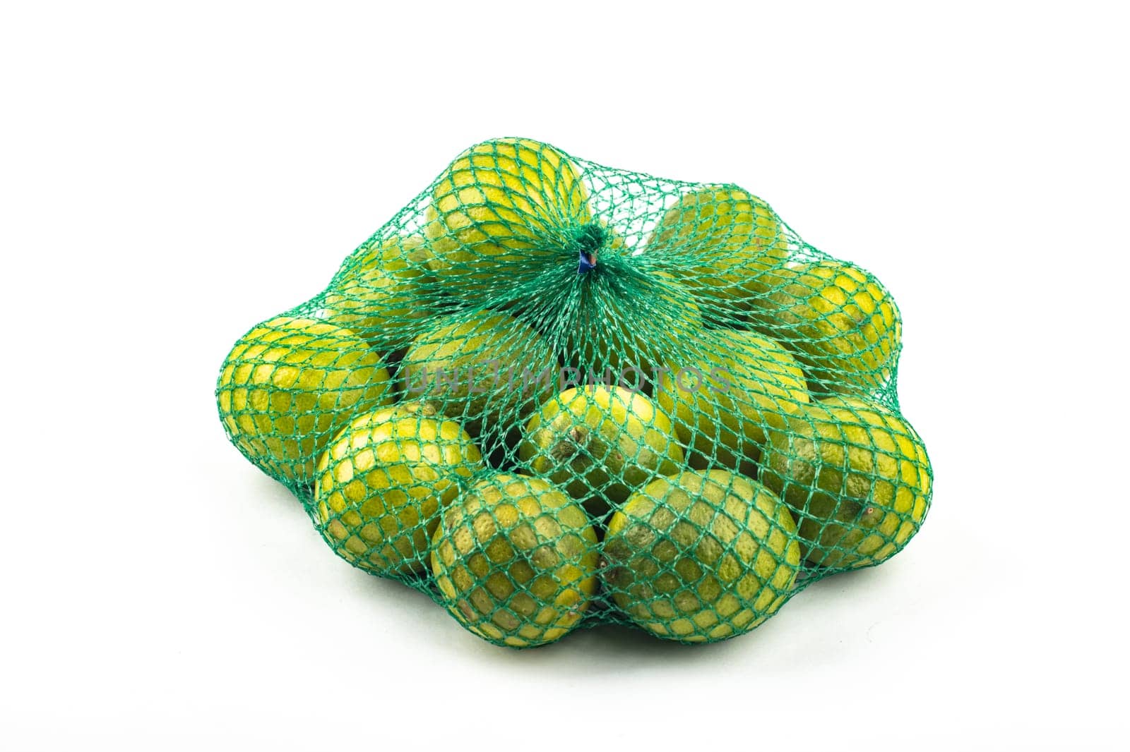 Fresh limes in the net green lime citrus fruit stand isolated on white background. Lime wedge with clipping path
