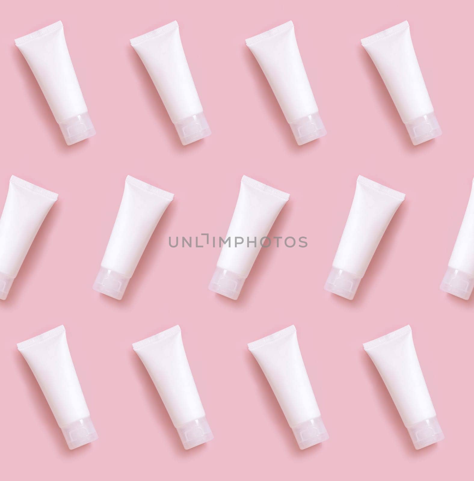 White plastic cream tube on light pink, pattern, top view, cosmetic mockup. Skincare beauty product, cream or lotion. Exotic natural cosmetics, pastel minimal composition..