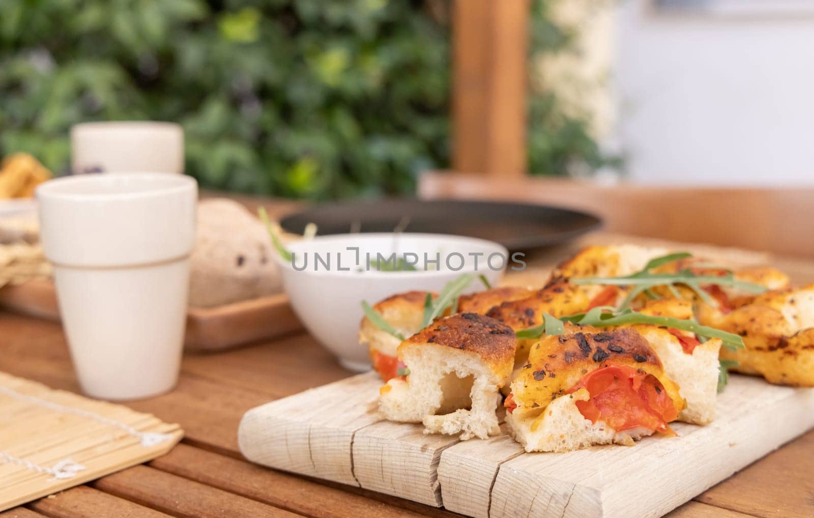 Italian summer appetizer focaccia with cherry tomatoes and rucola served outdoor with glasses of red wine. Tipical Apulian Dried bread, made in Salento. Local cousine. Vegetarian food
