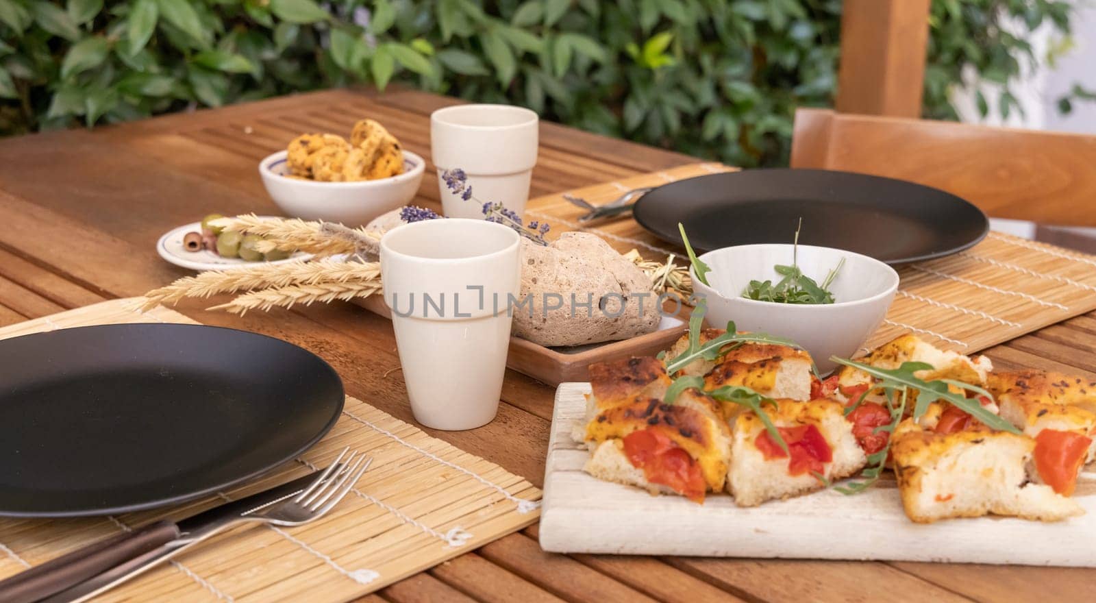 Italian summer appetizer focaccia with cherry tomatoes and rucola served outdoor with glasses of red wine. Tipical Apulian Dried bread, made in Salento. Local cousine. Vegetarian food